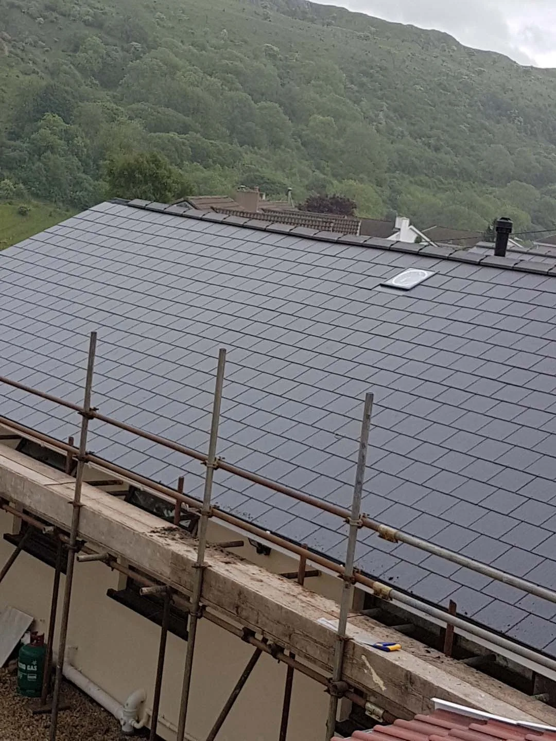 Large finished slate roof on a bungalow with a rooflight and flue