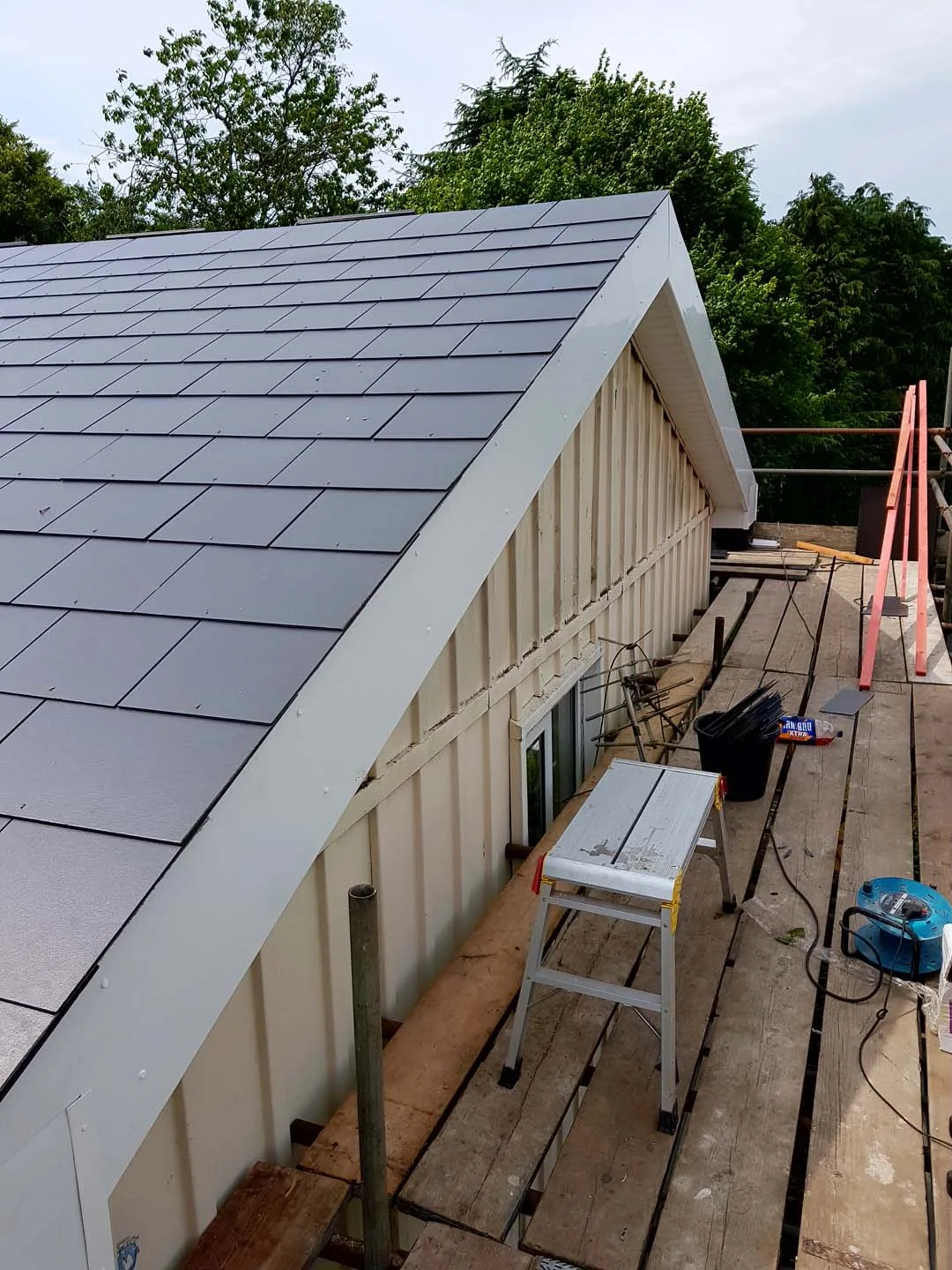 New slate roof on a clad bungalow with a wide white PVC bargeboard at the gable