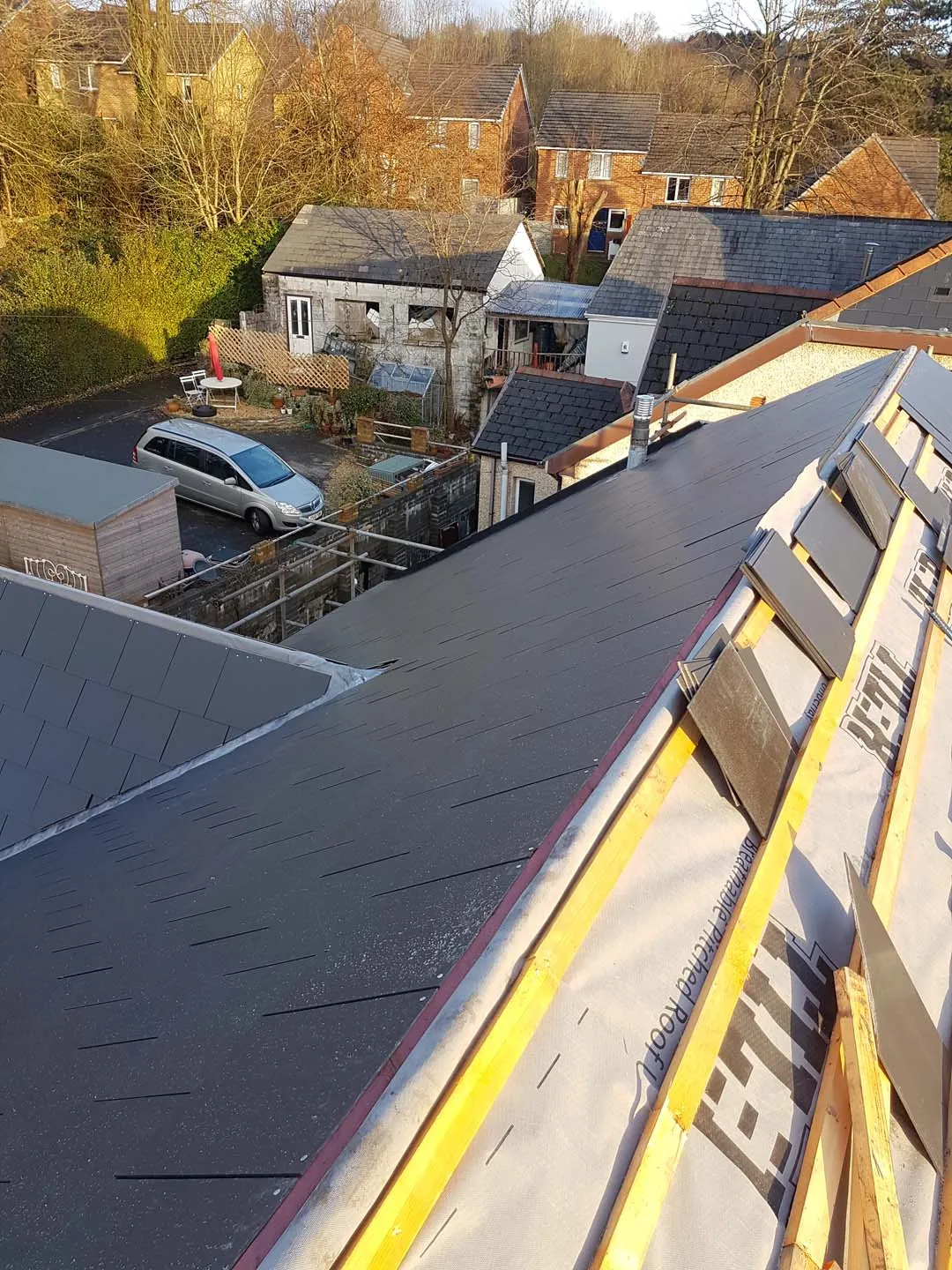 New slate roof meeting a dormer roof with a lead valley, with membrane and battens on the next slope