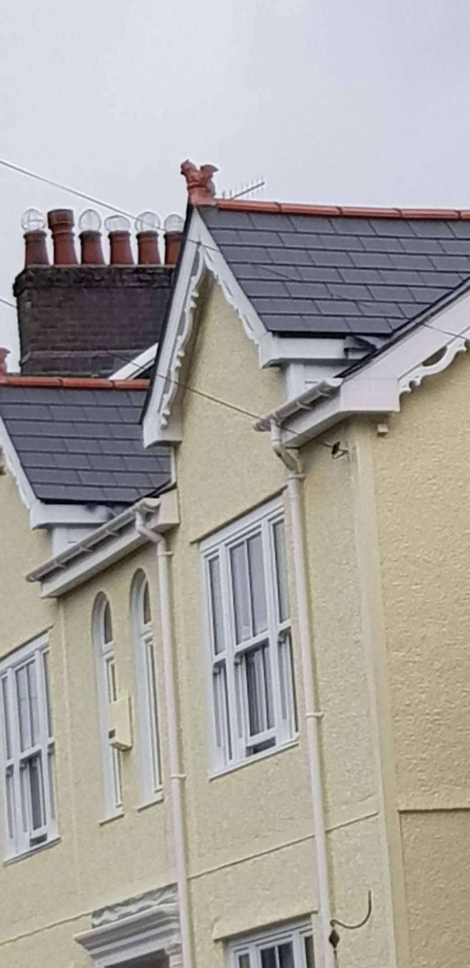 Victorian house gables re-roofed in grey slate with red clay ridge, decorative finial and ornate white bargeboards